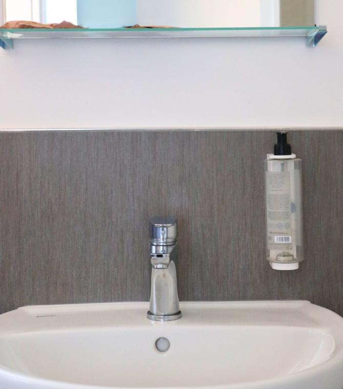 Lavandino con dispenser di sapone e mensola in bagno moderno.